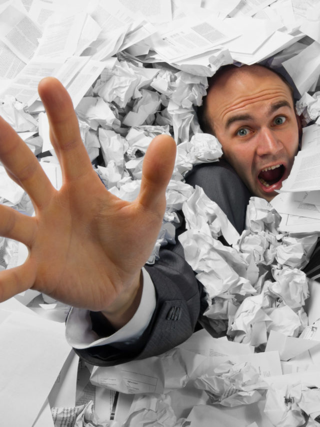 Businessman sinking in heap of documents