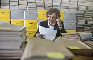 Businessman sitting at desk Overloaded With Paperwork