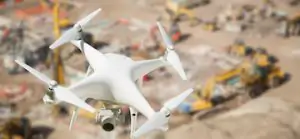 Unmanned Aircraft System (UAV) Quadcopter Drone In The Air Over Construction Site.