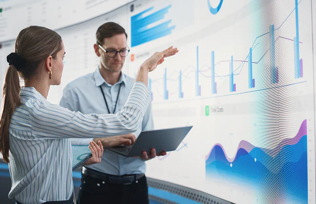 Professionals analyzing historical data visualizations on a large digital display